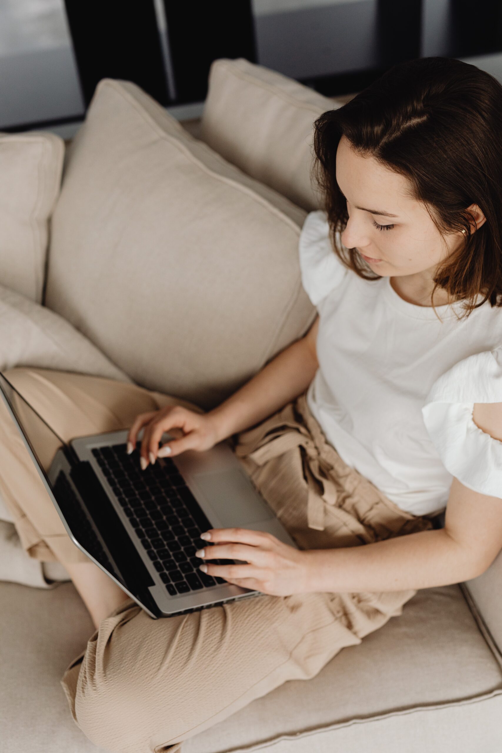 A woman sitting on the couch using her laptop.